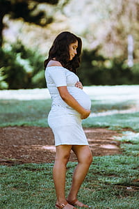 pregnant woman standing on grass during daytime thumbnail