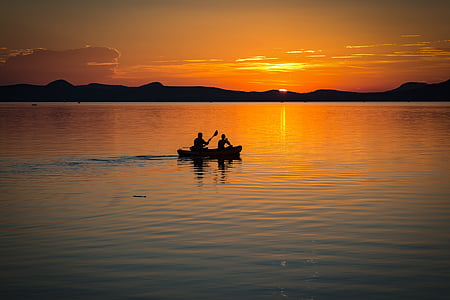 silhouette photography of two person on boat sailing during golden hour thumbnail