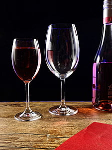 filled clear wine glass beside empty water goblet beside wine empty bottle on top of table thumbnail