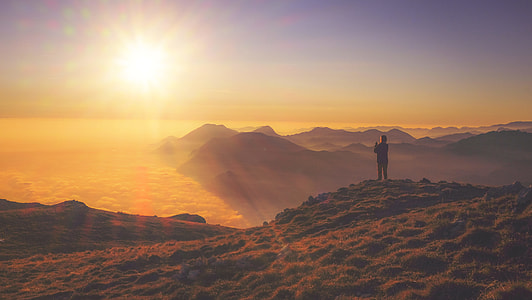 silhouette of person standing on top of mountain at sunrise thumbnail
