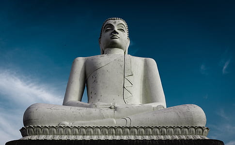 low-angle photography of white Buddha statue under clear blue sky thumbnail