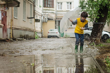 boy walking holding umbrella during daytime thumbnail