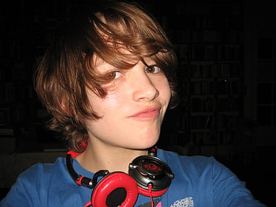 person wearing black and red corded headphones and blue shirt taking selfie and smiling thumbnail