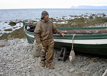 man wearing raincoat standing beside fishing boat thumbnail