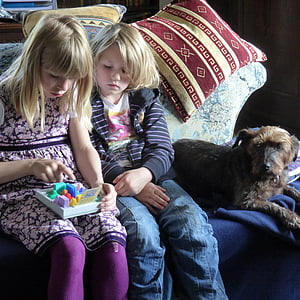 two girls playing toy while sitting on couch thumbnail