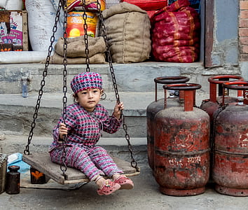 girl sitting on hanging swing near propane tanks thumbnail