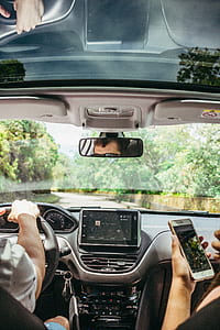 woman using iPhone beside man driving vehicle thumbnail