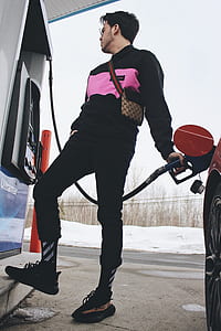 man refilling gas on red car on gas station thumbnail