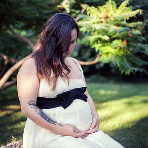 pregnant woman sitting beside grass field thumbnail