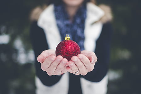 selective focus photography of woman holding Christmas bauble thumbnail