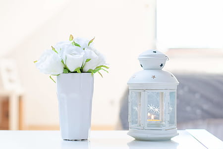 Candle Inside White Candle Lantern Beside White Flower Arrangement thumbnail