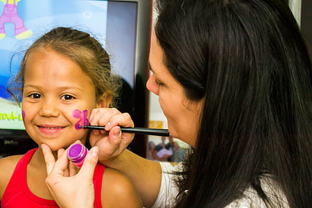 woman painting a purple flower on the face a girl thumbnail