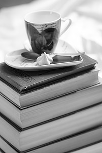 greyscale photo of teacup on top book stack thumbnail