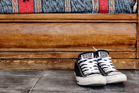 pair of black-and-white Converse low-top sneakers besides brown wooden panel thumbnail