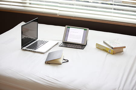 Macbook Pro over White Fabric Sheet Beside White Ipad thumbnail