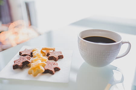 White Tea Cup Beside White Square Saucer With Star Shaped Cookies thumbnail