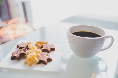 several star cookies on square white ceramic dish beside coffee filled white milk glass hobnail mug on top of table thumbnail