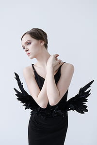 woman wearing black spaghetti-strap dress standing beside white background thumbnail