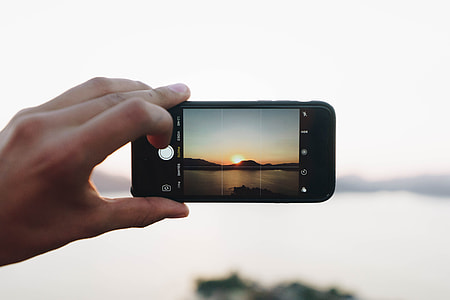 person holding black smartphone taking photo of golden hour thumbnail