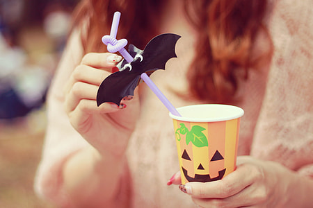 person holding a orange, white and yellow Halloween plastic cup with straw thumbnail