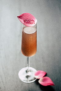 champagne flute with brown liquid with pink petal lid thumbnail