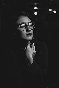 grayscale photography of woman both hands on her neck collar wearing hippie eyeglasses thumbnail