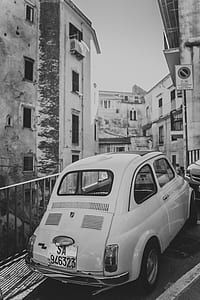 grayscale photography of car parked beside building thumbnail