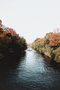 river with boat passing by under white sky thumbnail