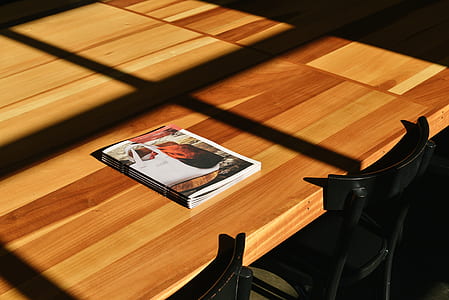 magazine on top of rectangular beige wooden table thumbnail
