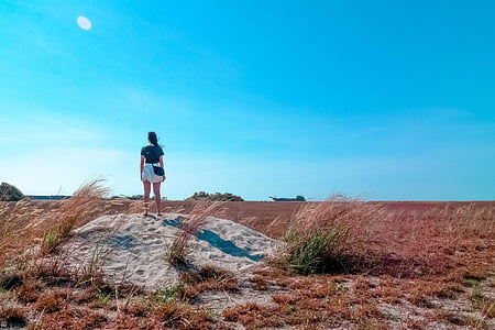 woman standing on brown sand during daytime thumbnail