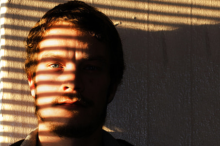 man's face on window stripes shadow effect during daytime thumbnail