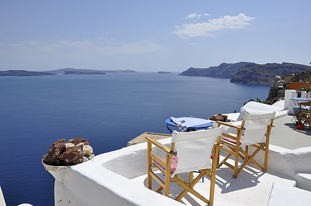 two white-and-brown chairs on white terrace facing body of water thumbnail