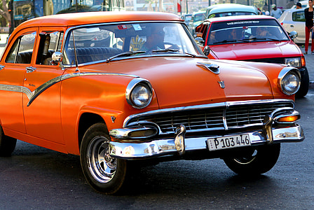 classic orange sedan on road near red vehicle thumbnail