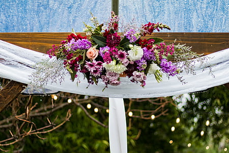 assorted flower swag bouquet on brown wooden wedding arch thumbnail
