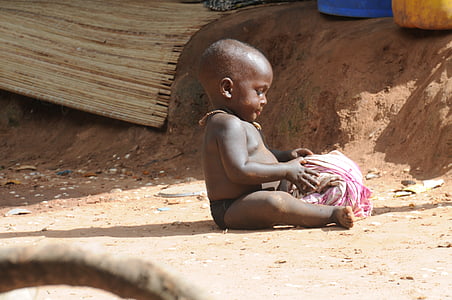 child sitting on ground holding pink textile thumbnail