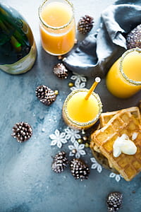 green bottle with three drinking glasses filled with yellow beverage and pancake beside thumbnail