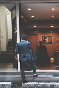 man wearing black suit holding handbag standing on concrete stair thumbnail