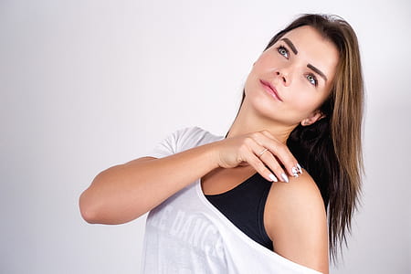 woman touching her shoulder near wall thumbnail
