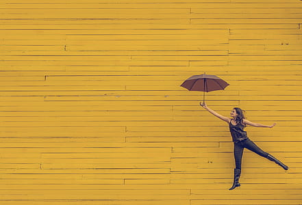 woman holding umbrella jumping on yellow background thumbnail