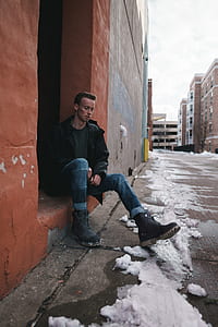 man in blue jeans sitting on brown floor thumbnail