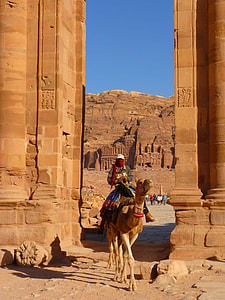 man riding camel by near arch thumbnail