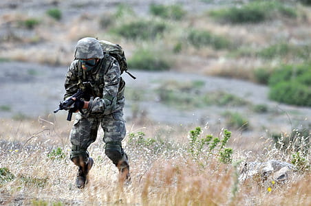 man wearing brown and gray camouflage overalls running uphill while holding SMG during daytime thumbnail