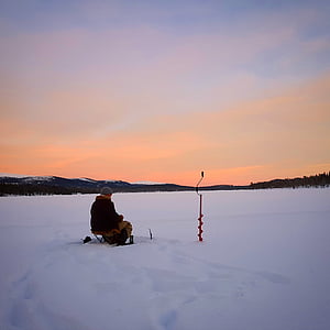 man sitting on chair surrounded with snow field thumbnail