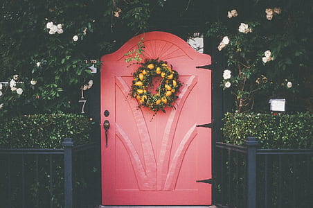 closeup photo of pink wooden door with green floral wreath thumbnail