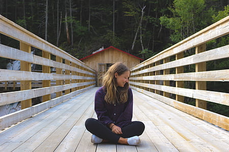 woman sitting down on beige wooden bridge thumbnail