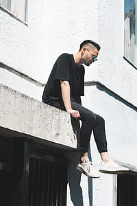 man sitting on side of concrete building thumbnail