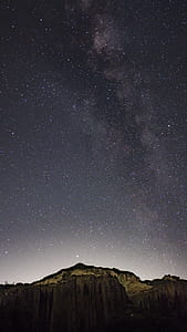 stars above rocky mountain during nighttime thumbnail