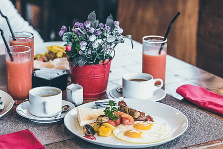 sunny side up egg and toasted bread on plate near two coffee mugs and juices thumbnail