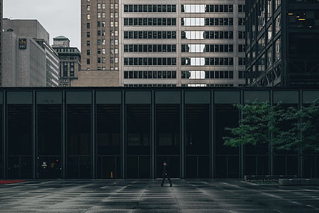 man walking towards black concrete building during daytime thumbnail