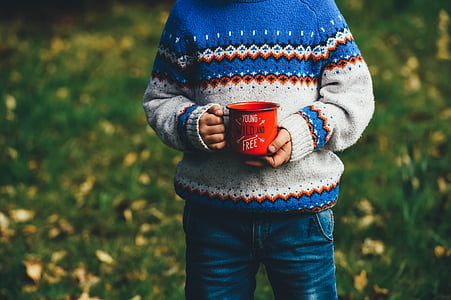 boy in blue, white, and brown sweater holding coffee mug thumbnail